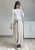 Eleganckie spodnie beżowe z wiązaniem w pasie szeroka nogawka styl casual chic Beżowe spodnie z wysokim stanem i kopertowym przodem stylizacja damska na co dzień