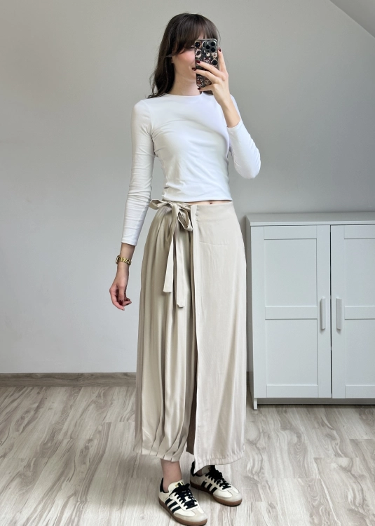 Eleganckie spodnie beżowe z wiązaniem w pasie szeroka nogawka styl casual chic Beżowe spodnie z wysokim stanem i kopertowym przodem stylizacja damska na co dzień