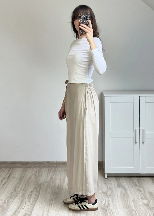 Luźne spodnie kopertowe beżowe miękka tkanina wygodny fason styl nowoczesny Spodnie beżowe szerokie nogawki wiązanie w talii outfit elegancko codzienny