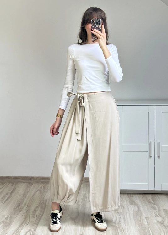 Minimalistyczne spodnie kopertowe w kolorze beżowym stylizacja basic outfit Beżowe spodnie z szeroką nogawką i zakładanym przodem styl miejski casual