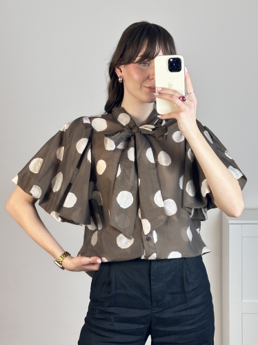 Stylizacja z brązową bluzką w groszki (polka dot) i czarnymi spodniami z wysokim stanem.